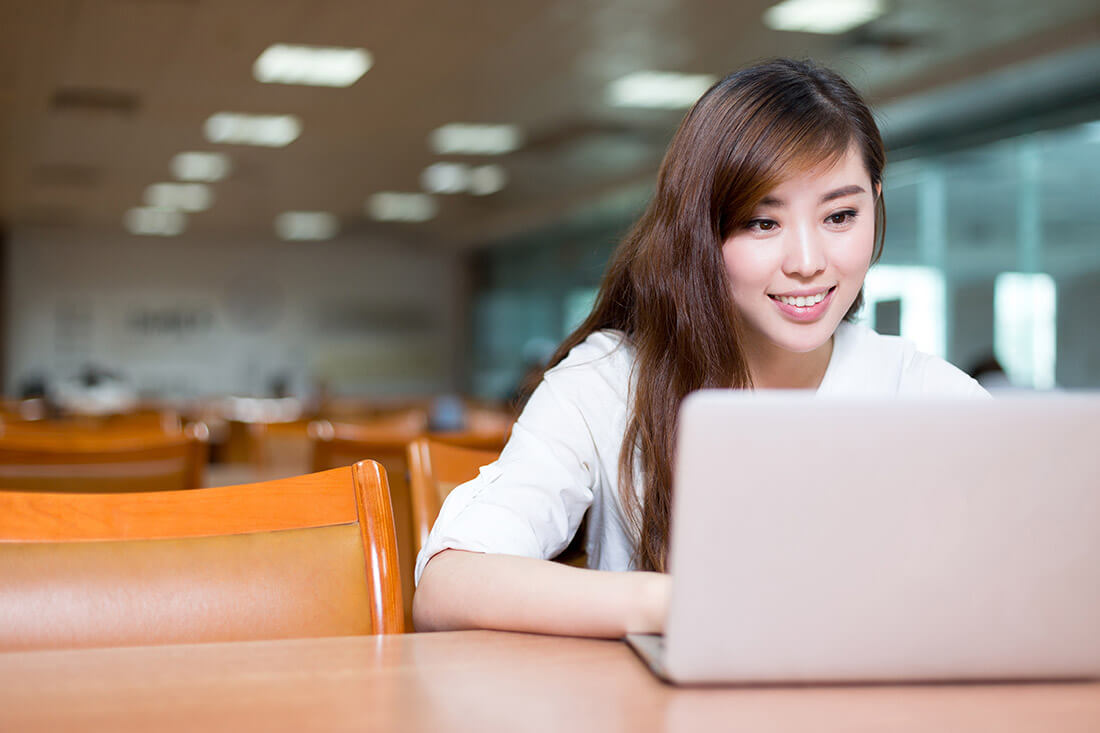 Asian beautiful female student study in library with laptop.